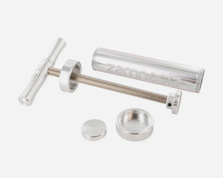 Une seringue métallique argentée avec une poignée et un piston.