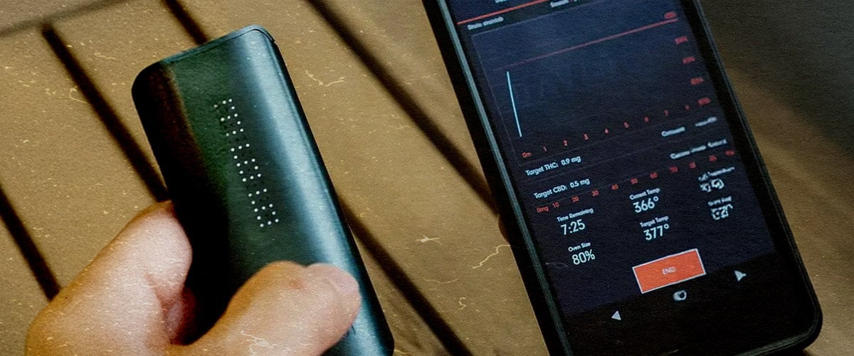 Vaporisateur DaVinci IQ3 : Fonctions de nouvelle génération et performance supérieure Vaporisateur PAX IQ3 avec appli montrant 80 % de batterie, THC 0,5 mg et 366 °F, tenu à côté d’un téléphone sur une table en bois.