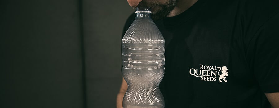 Personne inhalant de la fumée d'un bong à gravité fabriqué à partir d'une bouteille en plastique