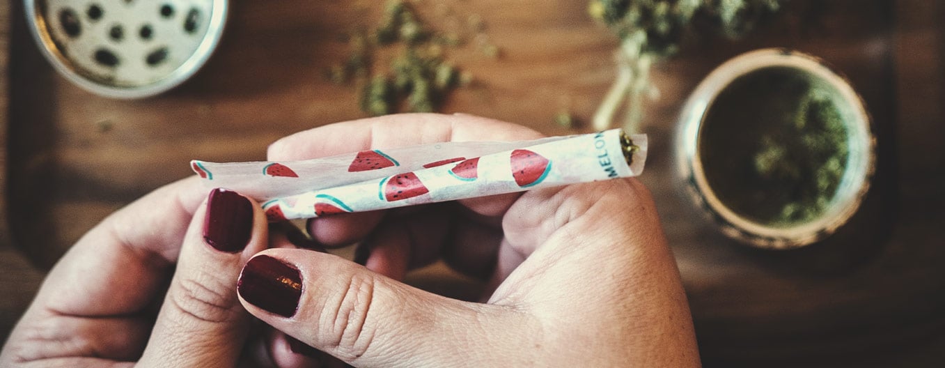 Personne en train de rouler un joint avec des papiers à rouler à motif de pastèque.