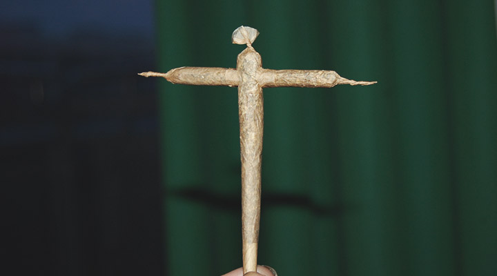 Joint de cannabis roulé en forme de croix posé sur une surface plate, mettant en évidence ses détails et sa structure.