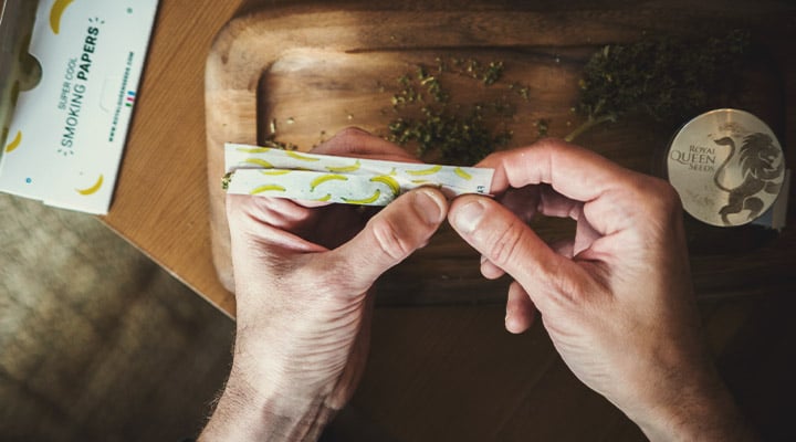 Personne en train de rouler un joint avec des papiers à rouler au goût banane.
