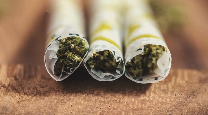 Trois joints roulés avec des fleurs de cannabis et du papier à rouler au goût de banane.