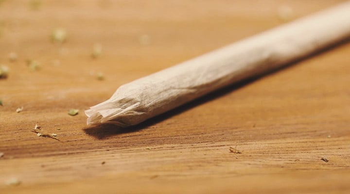 Joint roulé prêt à être fumé, avec une apparence propre et compacte, posé sur une surface plane, mettant en valeur sa forme serrée et son papier d'enroulement."
