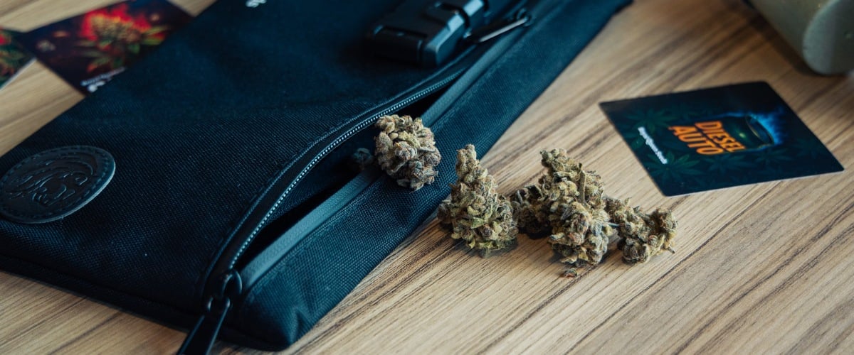 Sac de rangement discret pour stocker le cannabis Image d’un sac de rangement verrouillable avec des têtes de cannabis sur une surface en bois.