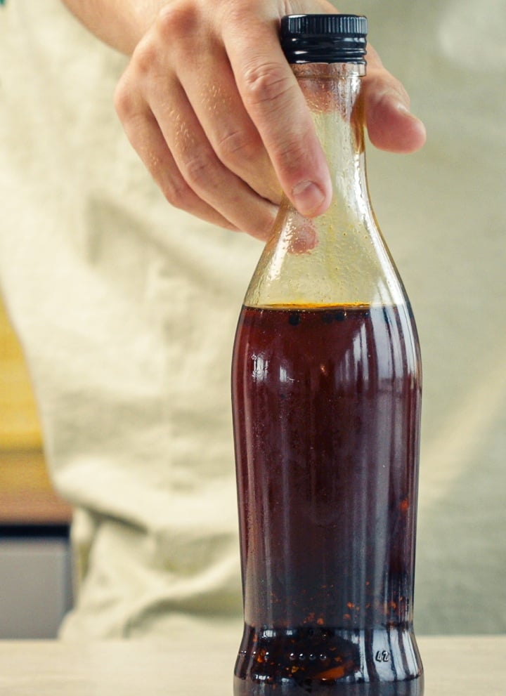 Étape 4 : Conserver Correctement l’Huile au Piment Infusée au Cannabis Bouteille en verre scellée remplie d’huile au piment infusée au cannabis, conservée dans une cuisine